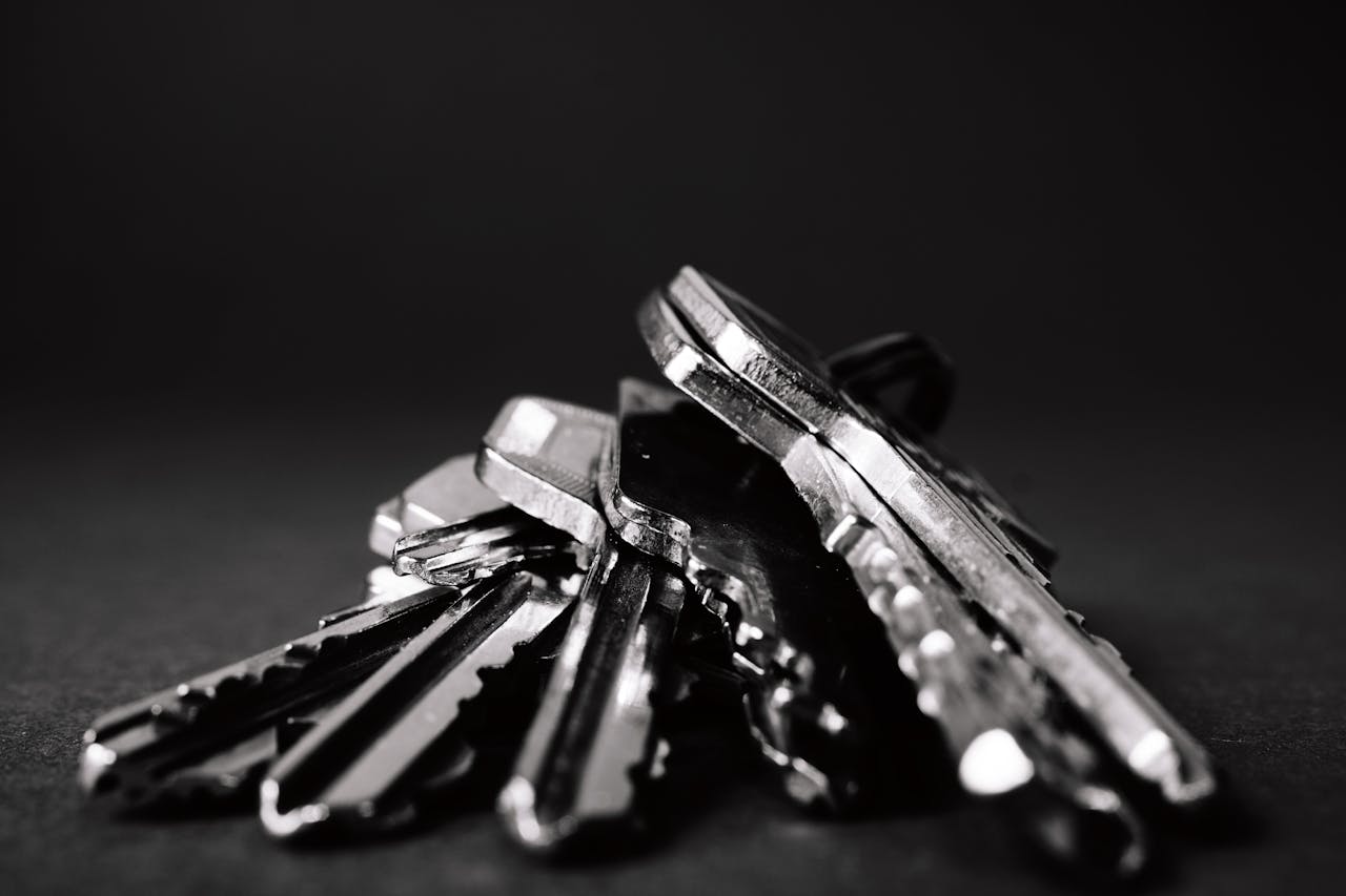 A close-up shot of a pile of metallic keys on a dark surface, emphasizing security and precision.